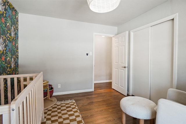 bedroom with a nursery area, dark hardwood / wood-style flooring, and a closet