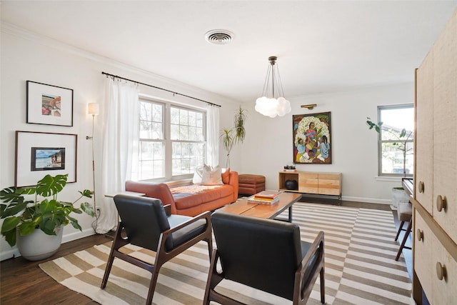 living room featuring hardwood / wood-style flooring, crown molding, and a notable chandelier