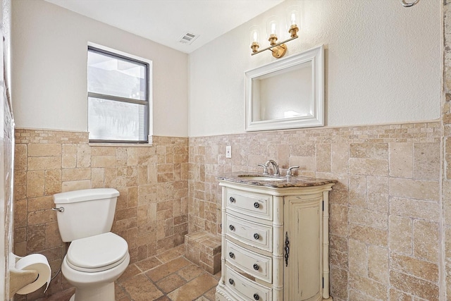 bathroom featuring tile walls, toilet, and vanity