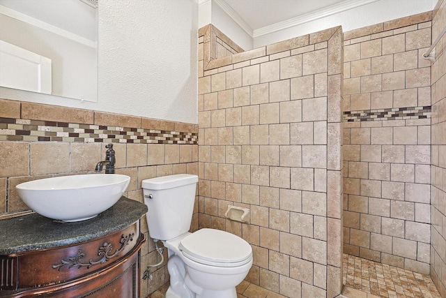 bathroom featuring tiled shower, tile walls, ornamental molding, toilet, and vanity