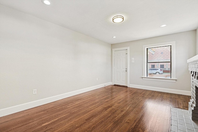 spare room with a fireplace and dark hardwood / wood-style floors