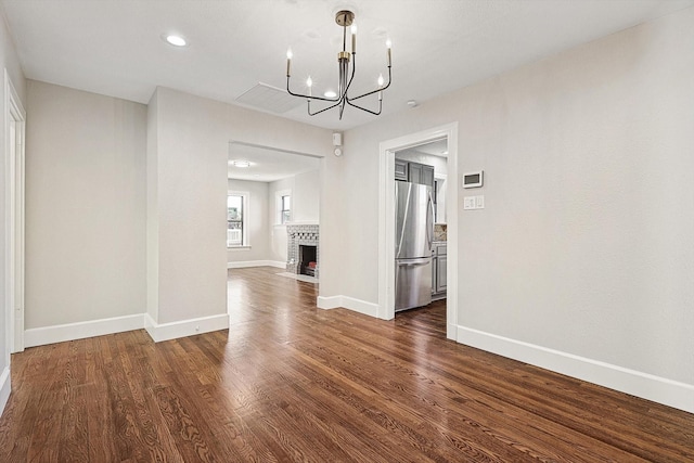 unfurnished dining area with dark hardwood / wood-style flooring, a fireplace, and a notable chandelier