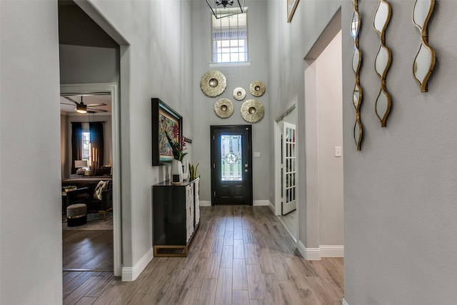 foyer entrance with a towering ceiling, light wood-type flooring, and ceiling fan