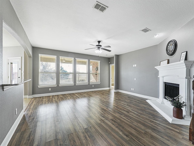 unfurnished living room with a textured ceiling, ceiling fan, and dark hardwood / wood-style floors