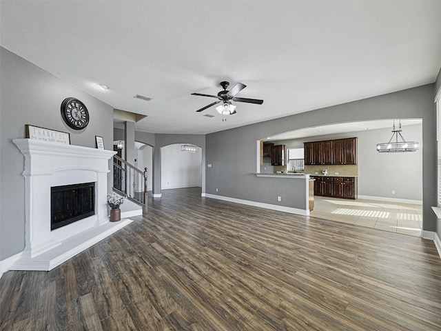 unfurnished living room featuring ceiling fan and dark wood-type flooring