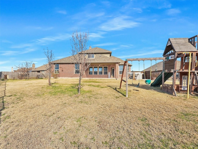 back of house with a yard and a playground