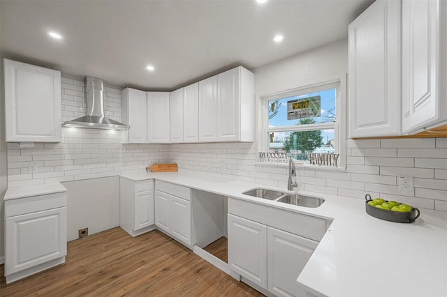 kitchen with light hardwood / wood-style floors, sink, white cabinetry, and wall chimney exhaust hood