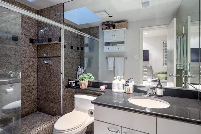 bathroom featuring walk in shower, a skylight, vanity, and toilet