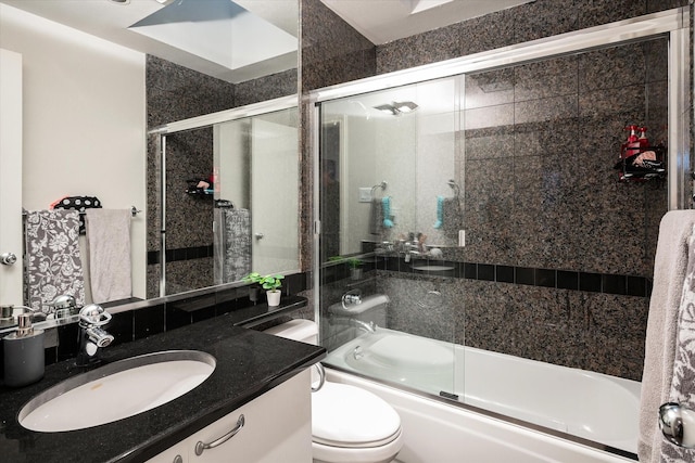 full bathroom featuring toilet, bath / shower combo with glass door, and vanity