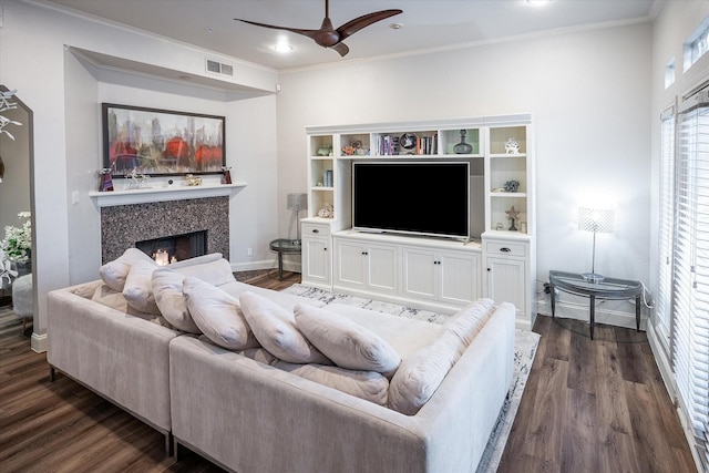 living room featuring dark wood-type flooring, ceiling fan, a fireplace, and ornamental molding