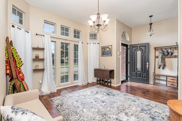 foyer entrance featuring dark hardwood / wood-style floors, an inviting chandelier, and a textured ceiling