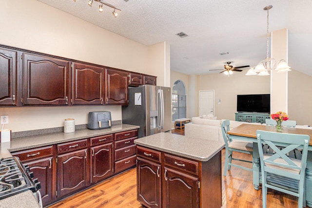 kitchen featuring stainless steel appliances, light wood-type flooring, a textured ceiling, pendant lighting, and a center island