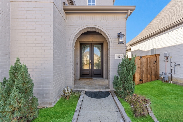 view of exterior entry featuring french doors and a yard