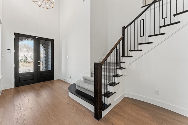 entrance foyer featuring a high ceiling, french doors, an inviting chandelier, and hardwood / wood-style flooring