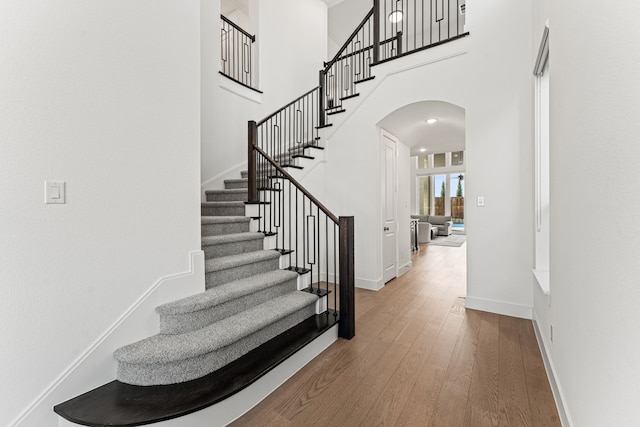 stairway with a towering ceiling and hardwood / wood-style flooring