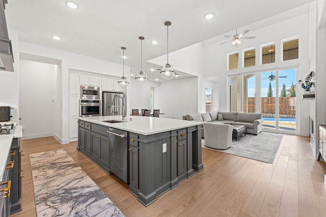 kitchen with sink, white cabinets, pendant lighting, a kitchen island with sink, and appliances with stainless steel finishes