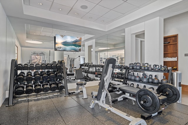 gym featuring a tray ceiling and a drop ceiling