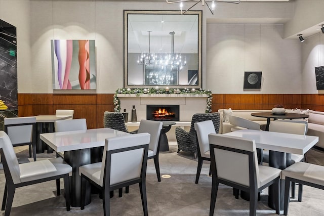 dining space featuring concrete floors, wood walls, a chandelier, and a fireplace