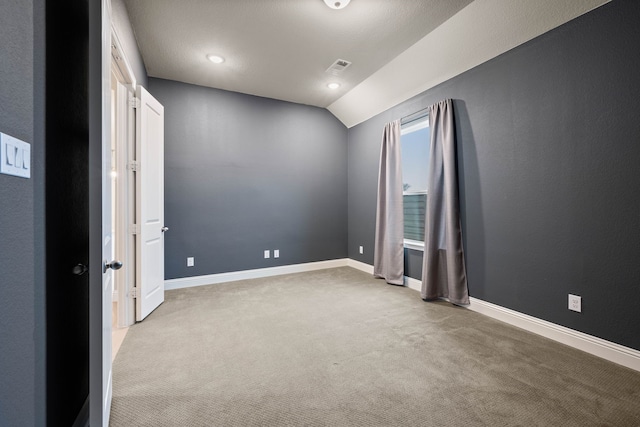 empty room featuring lofted ceiling and light carpet