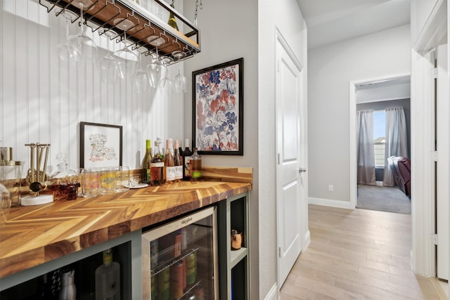 bar with butcher block counters, beverage cooler, and light hardwood / wood-style floors