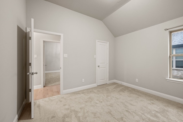 unfurnished bedroom featuring light colored carpet and vaulted ceiling