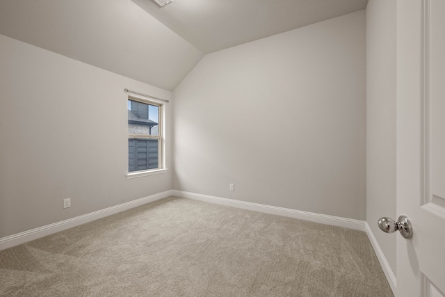 empty room with light colored carpet and vaulted ceiling