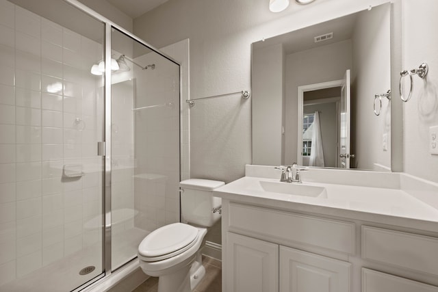 bathroom featuring vanity, a shower with door, and toilet