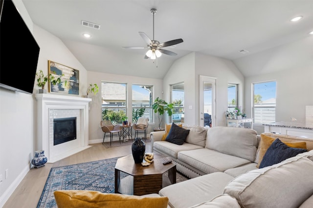 living room featuring ceiling fan, a fireplace, a healthy amount of sunlight, and light wood-type flooring