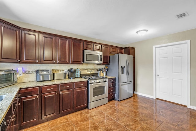 kitchen featuring light stone counters, appliances with stainless steel finishes, tile patterned floors, and tasteful backsplash