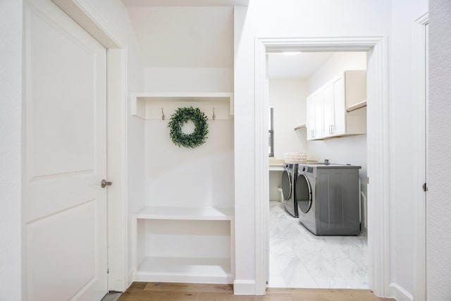 laundry area with hardwood / wood-style floors, separate washer and dryer, and cabinets