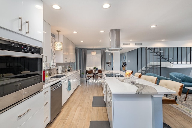 kitchen with island range hood, decorative light fixtures, stainless steel appliances, white cabinetry, and sink