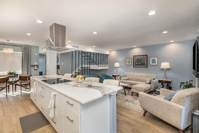 kitchen with white cabinets, light hardwood / wood-style floors, island range hood, a kitchen island, and black electric stovetop