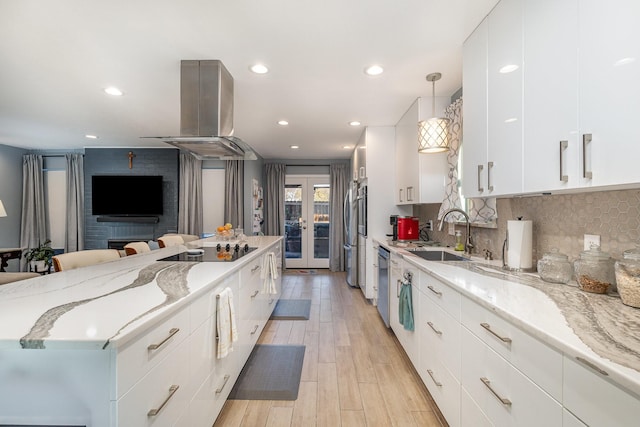 kitchen with white cabinets, light stone countertops, french doors, sink, and decorative light fixtures