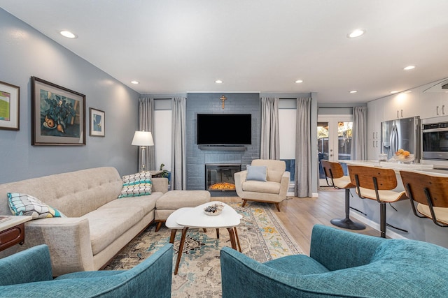 living room with french doors, light wood-type flooring, and a brick fireplace