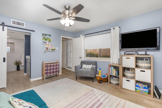 living area with ceiling fan and a barn door