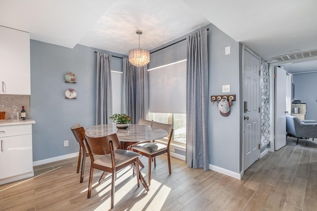 dining room featuring light wood-type flooring and a notable chandelier