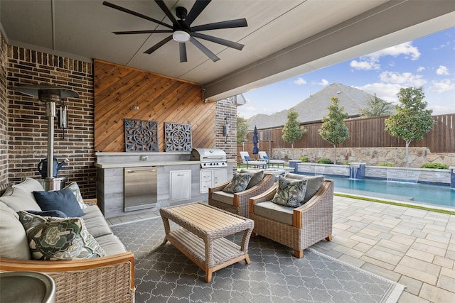 view of patio / terrace with an outdoor hangout area, grilling area, exterior kitchen, ceiling fan, and pool water feature