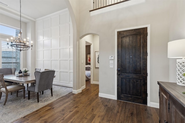 entryway featuring a chandelier, ornamental molding, and dark wood-type flooring