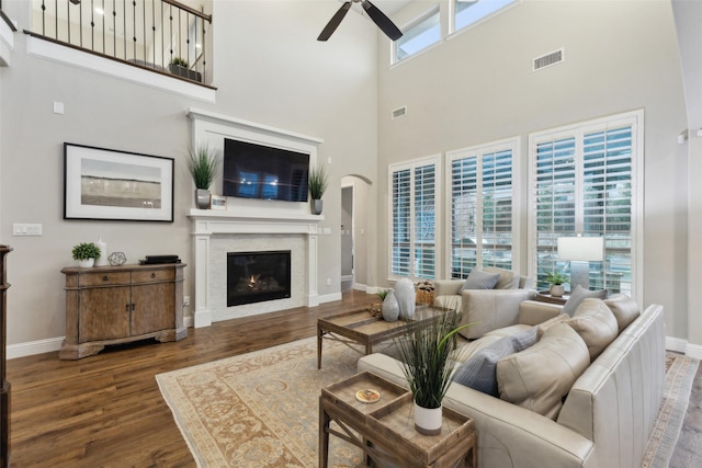 living room with a high ceiling, ceiling fan, and dark hardwood / wood-style floors