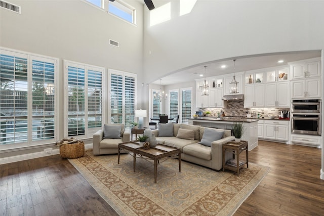 living room featuring a healthy amount of sunlight, dark wood-type flooring, and a high ceiling