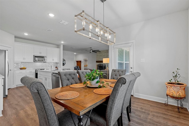 dining room featuring ceiling fan with notable chandelier and wood-type flooring