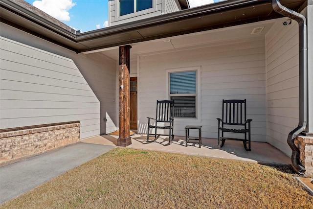 doorway to property with covered porch and a lawn