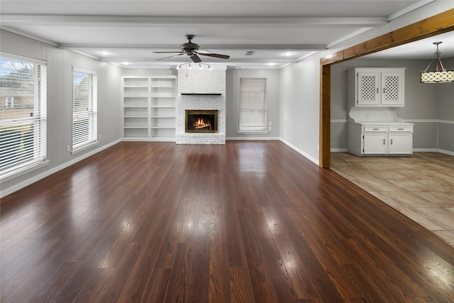 unfurnished living room with dark hardwood / wood-style flooring, a brick fireplace, ceiling fan, and built in features