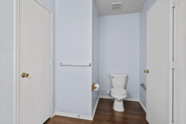 bathroom with a textured ceiling, toilet, and wood-type flooring