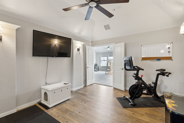 workout room with light wood-type flooring and vaulted ceiling