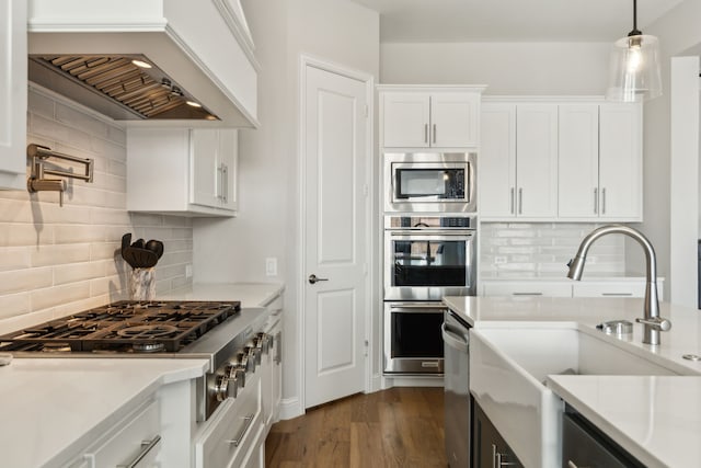 kitchen featuring premium range hood, stainless steel appliances, backsplash, white cabinetry, and sink