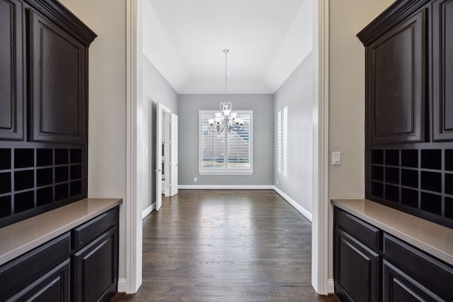 dining room featuring dark wood-style floors, a tray ceiling, baseboards, and an inviting chandelier