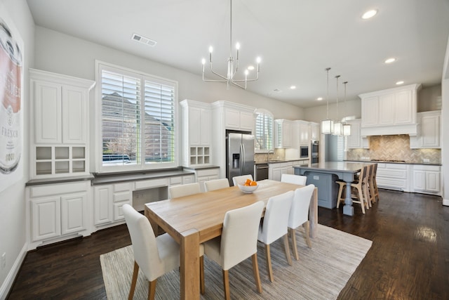 dining room featuring dark wood-type flooring, sink, and a chandelier