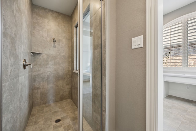 bathroom featuring a textured wall and a shower stall