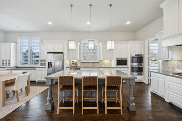 kitchen with white cabinetry, a kitchen island, appliances with stainless steel finishes, and pendant lighting